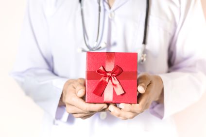 Un cadeau dans les mains d'une personne en blouse blanche
